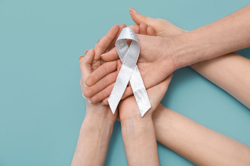 Hands holding a cancer awareness ribbon symbolizing support